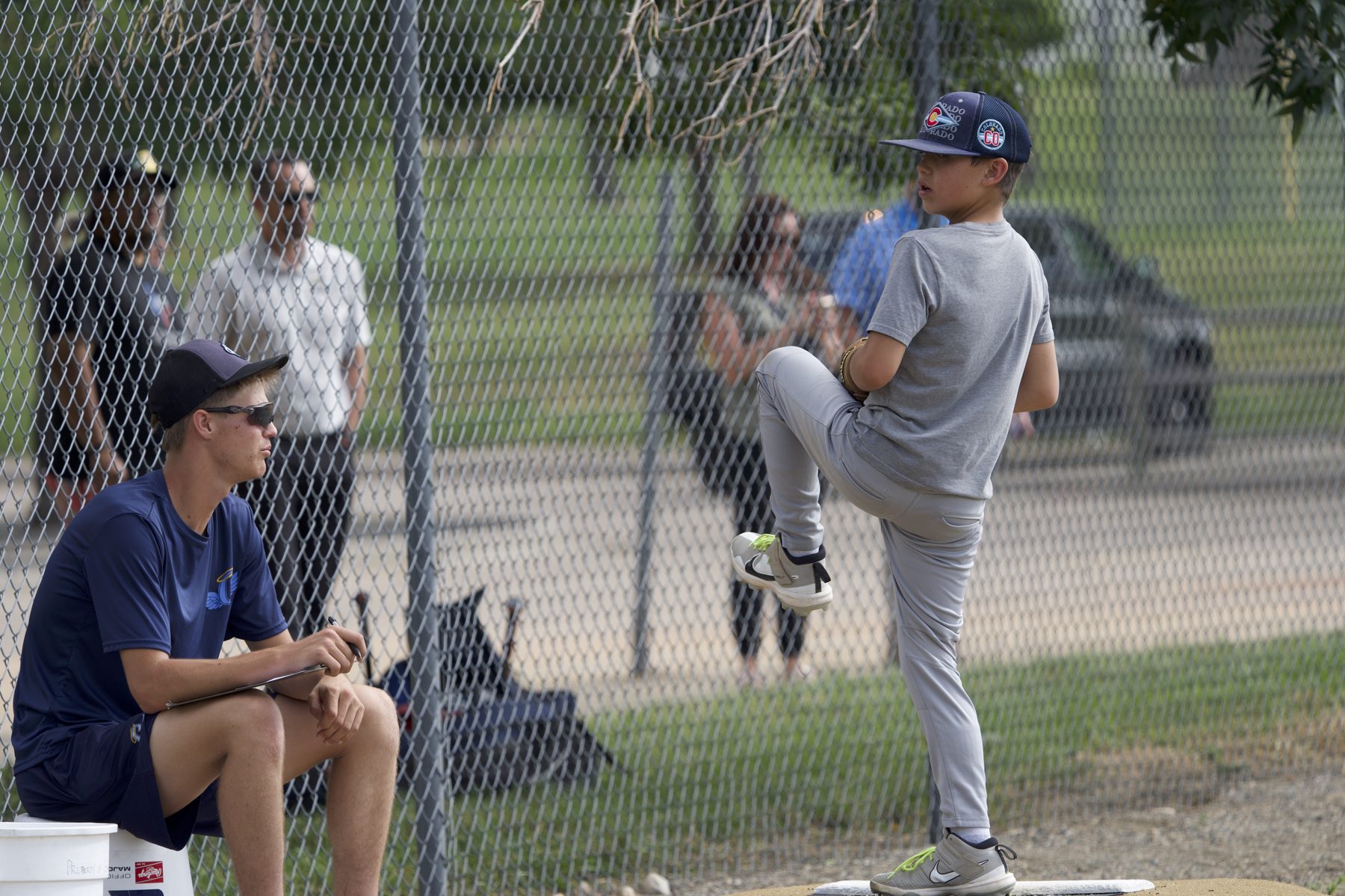 Youth pitcher at leg lift on the mound with coach evaluating