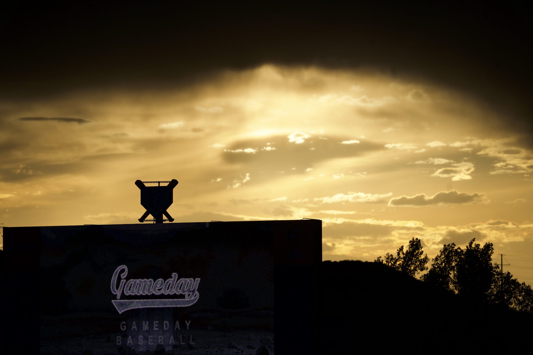 Gameday Baseball scoreboard silhouetted against a Colorado sunset