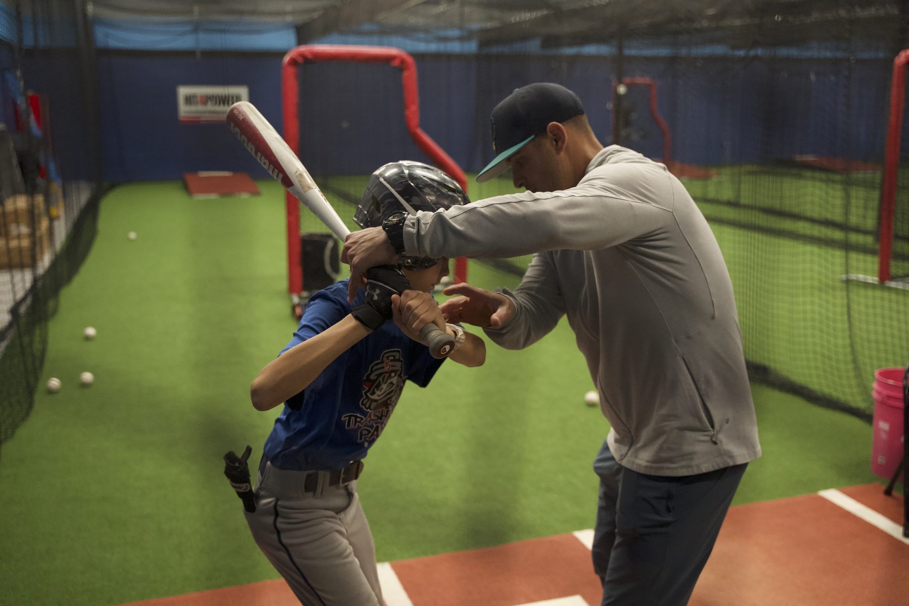 Gameday coach giving one-on-one hitting instruction to a youth player
