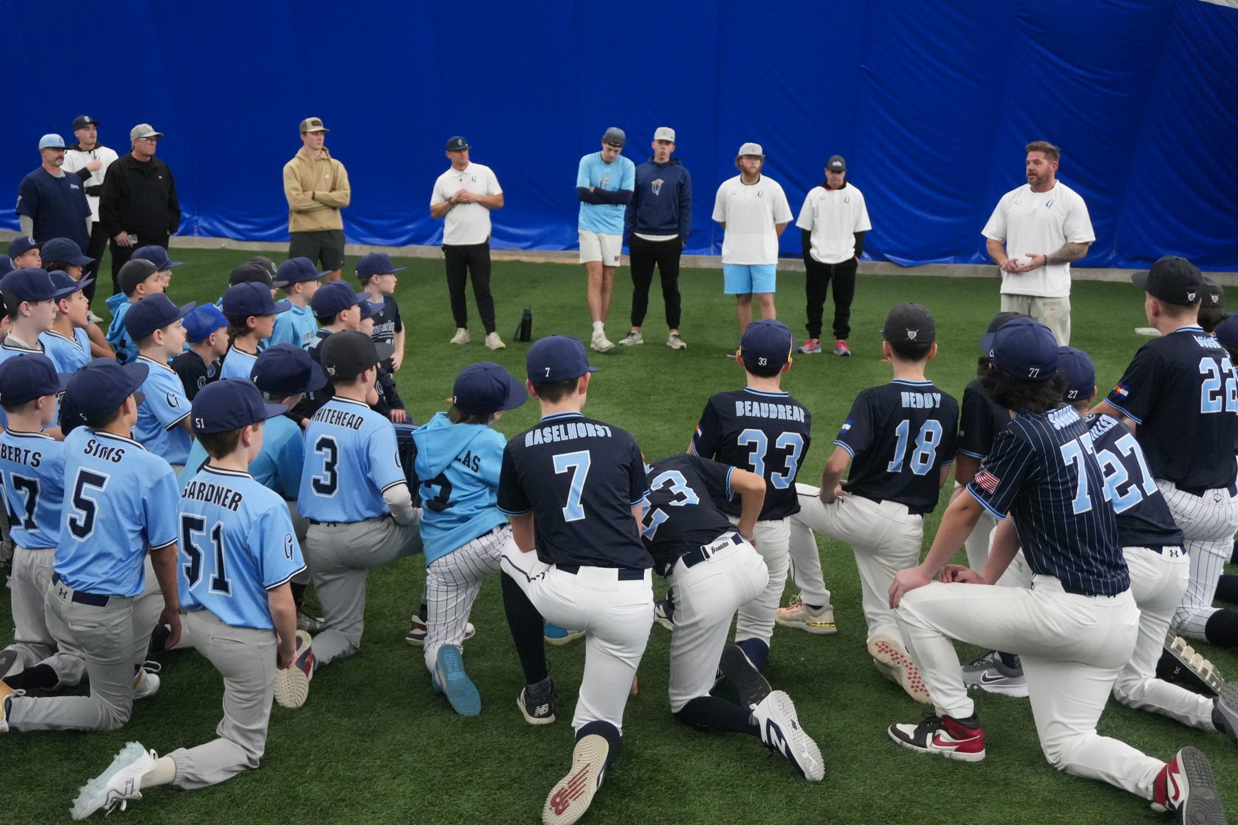 Gameday Baseball team huddle with coaches in the indoor facility