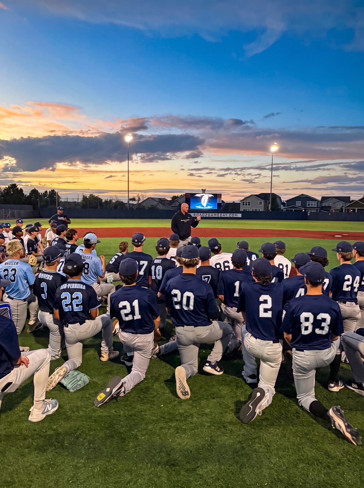 Gameday high school players gathered at dusk in front of the Road2Gameday scoreboard